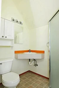 A bathroom with white walls and orange accents.