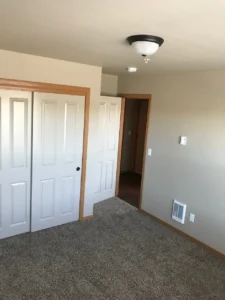 A bedroom with two doors and a ceiling fan.