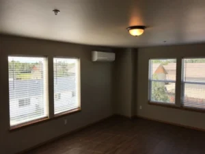 A room with three windows and a ceiling fan.